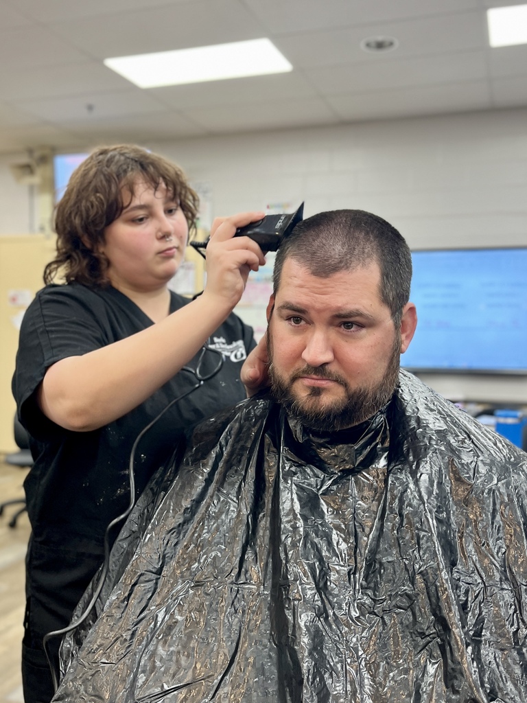Cosmetology student carefully uses clippers to shave the top of Mr. Entrekin’s head.