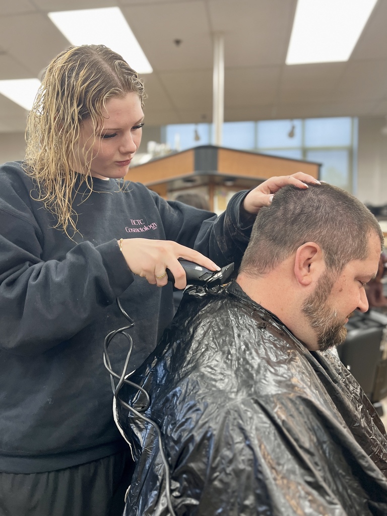 Cosmetology student uses clippers to shave the back of Mr. Entrekin’s head during the classroom celebration.