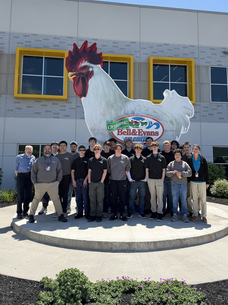 BCTC Mechatronics Engineering Technology students and staff pose outside Bell & Evans in front of a large chicken sign after a mini manufacturing summit.