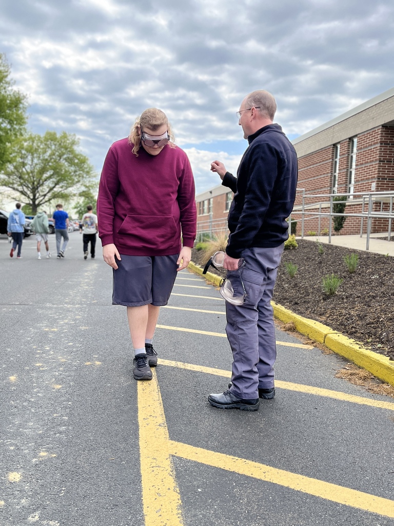 Student wearing goggles stands near a staff member during an outdoor Summer Sendoff activity.