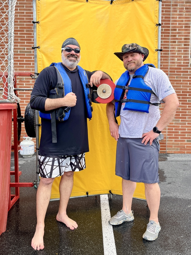 Two staff members pose in life vests beside the dunk tank during the Summer Sendoff.