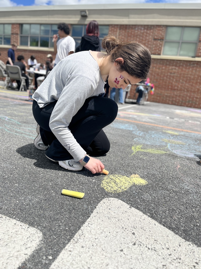 Student draws with sidewalk chalk during the Summer Sendoff.