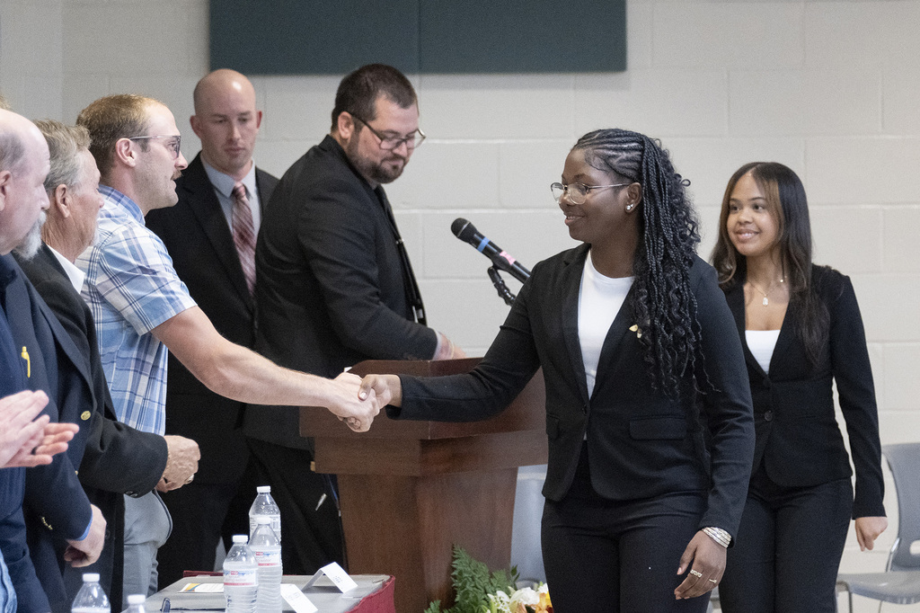 A BCTC student shakes hands with a school representative while receiving recognition at the JOC meeting.