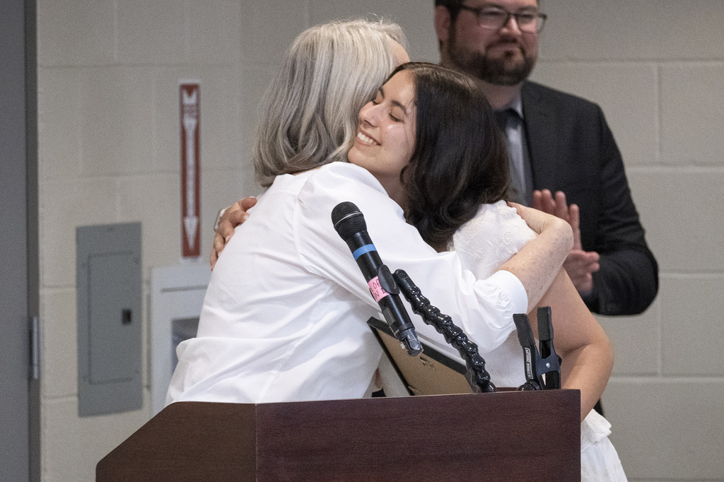 A BCTC student embraces a speaker at the podium during the JOC Scholarship recognition.