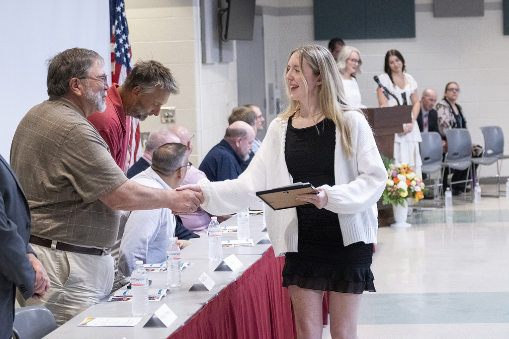 A BCTC student smiles while shaking hands with school representatives and receiving recognition.