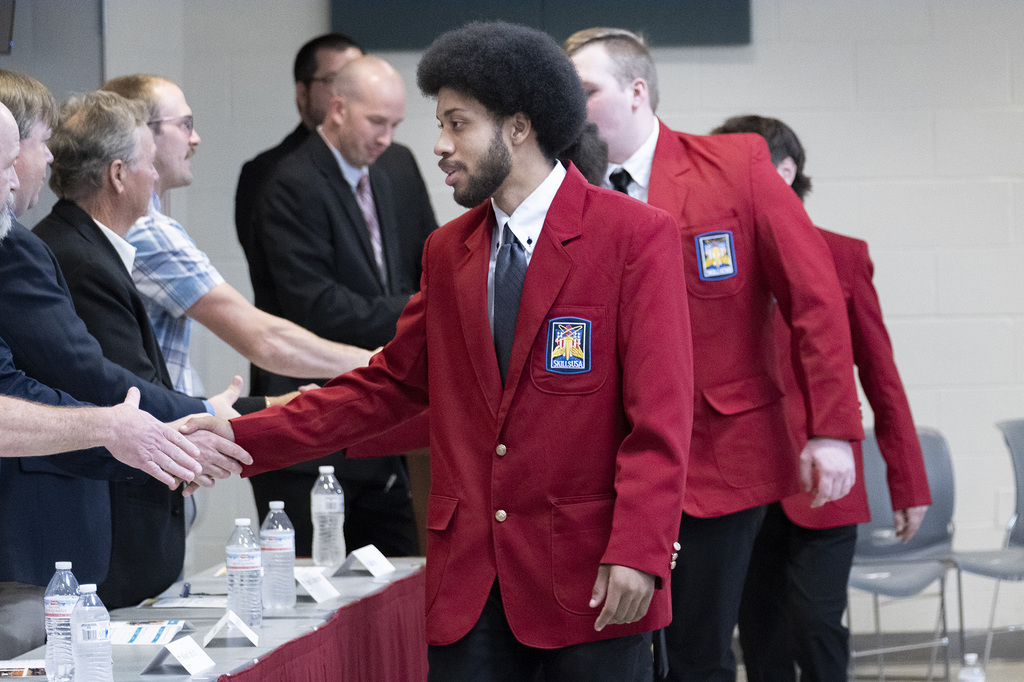 A SkillsUSA student in a red blazer shakes hands with a school representative during the JOC recognition.