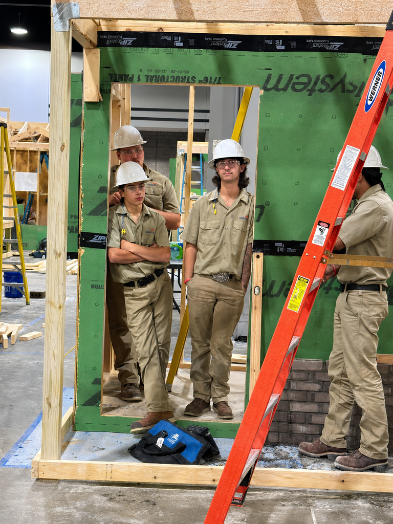 Construction competitors stand inside a framed structure during the SkillsUSA competition.