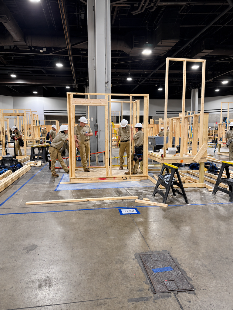 Competitors work on framed wooden walls inside the SkillsUSA competition area.