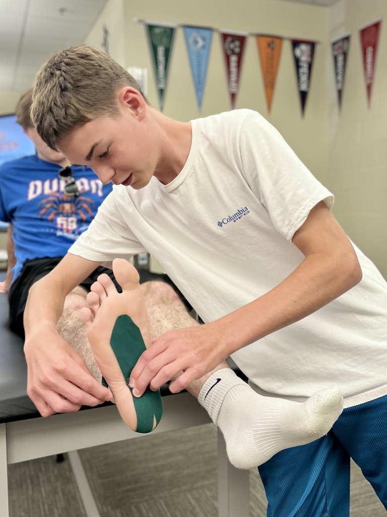 A Career Camp participant applies athletic tape to a classmate’s foot during a health skills activity.