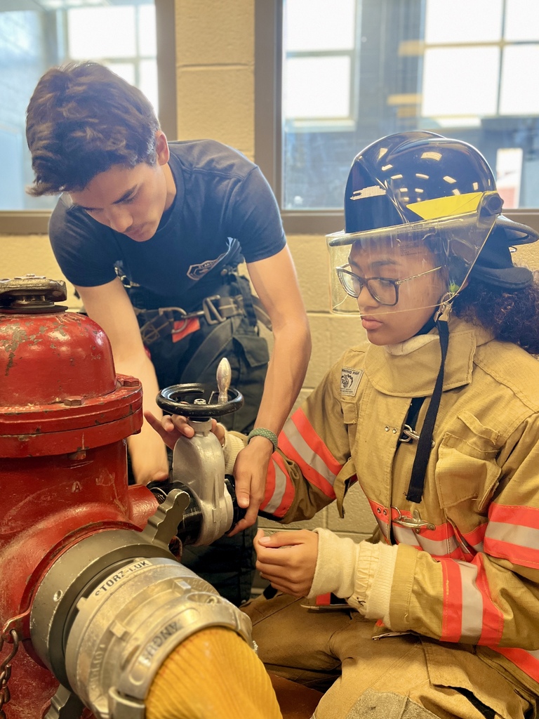 Career Camp participants wearing firefighter gear practice connecting a hose to a fire hydrant.