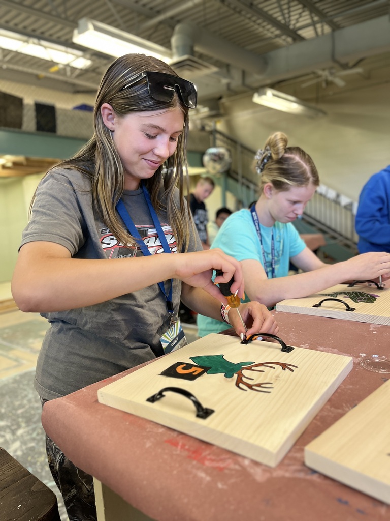 A Career Camp participant uses a screwdriver while assembling a decorated wooden project in a BCTC lab.