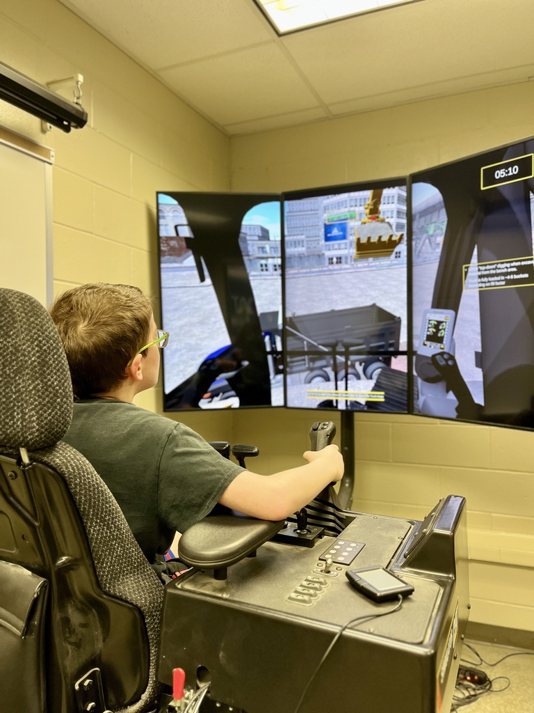 A Career Camp participant uses a heavy equipment simulator with hand controls and multiple screens.