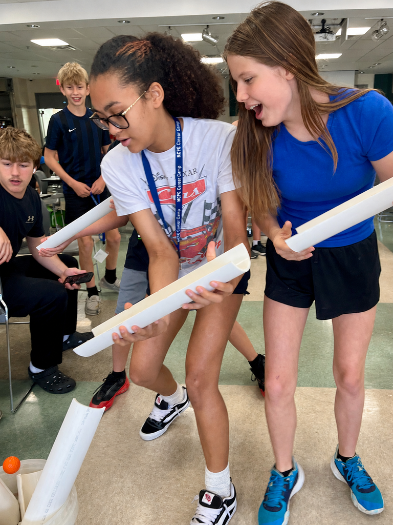 Career Camp participants use pipe pieces to guide an orange ball during a hands-on team-building activity.