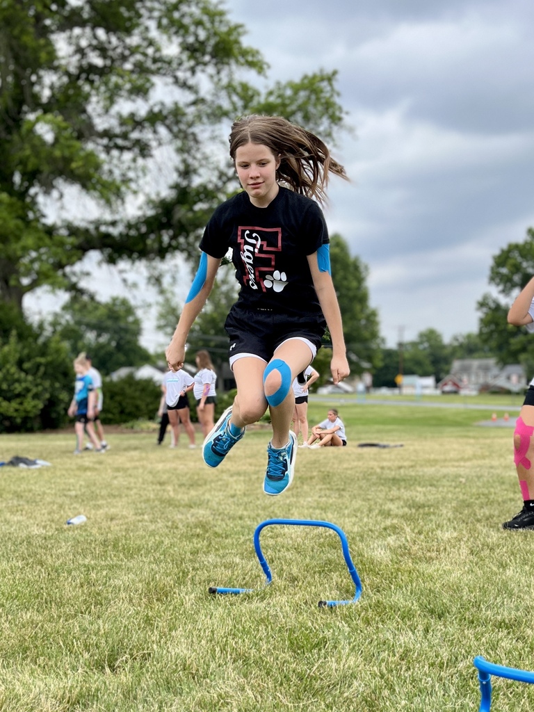 Career Camp participant jumps over a small hurdle during an outdoor athletic activity.