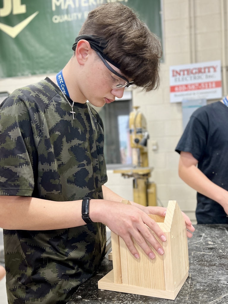 Career Camp participant wearing safety glasses assembles a wooden birdhouse project in a BCTC lab.