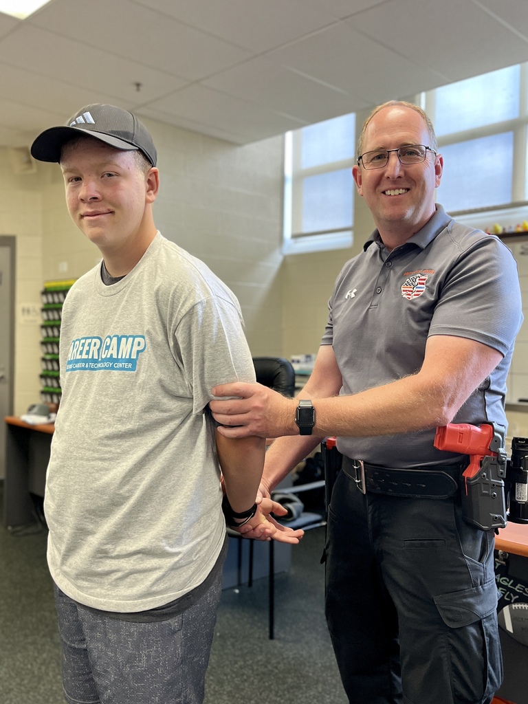Protective Services instructor demonstrates handcuffing techniques with a Career Camp participant.