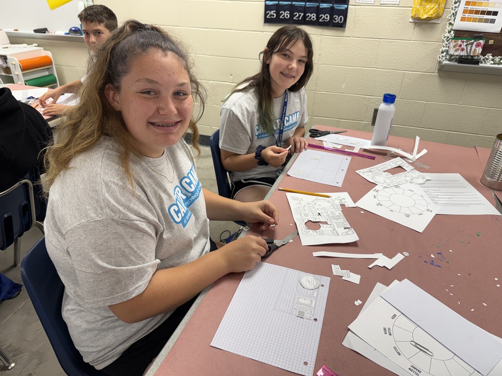 Career Camp participants work on paper design activities at a classroom table.