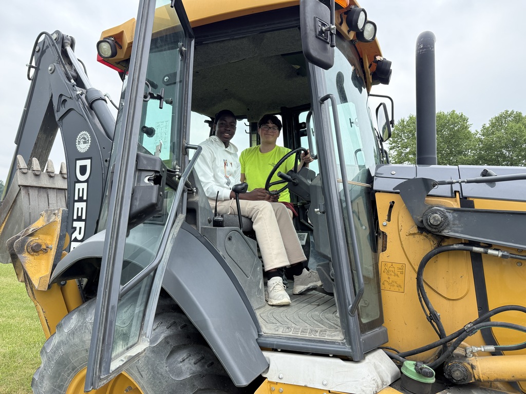 Two Career Camp participants sit inside the cab of a backhoe during a heavy equipment activity.