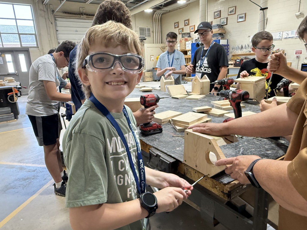 Career Camp participant smiles while working on a wooden birdhouse project in a BCTC lab.