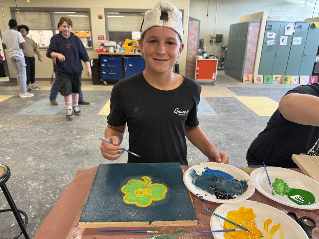 Career Camp participant displays a painted wooden board project during a hands-on workshop activity.