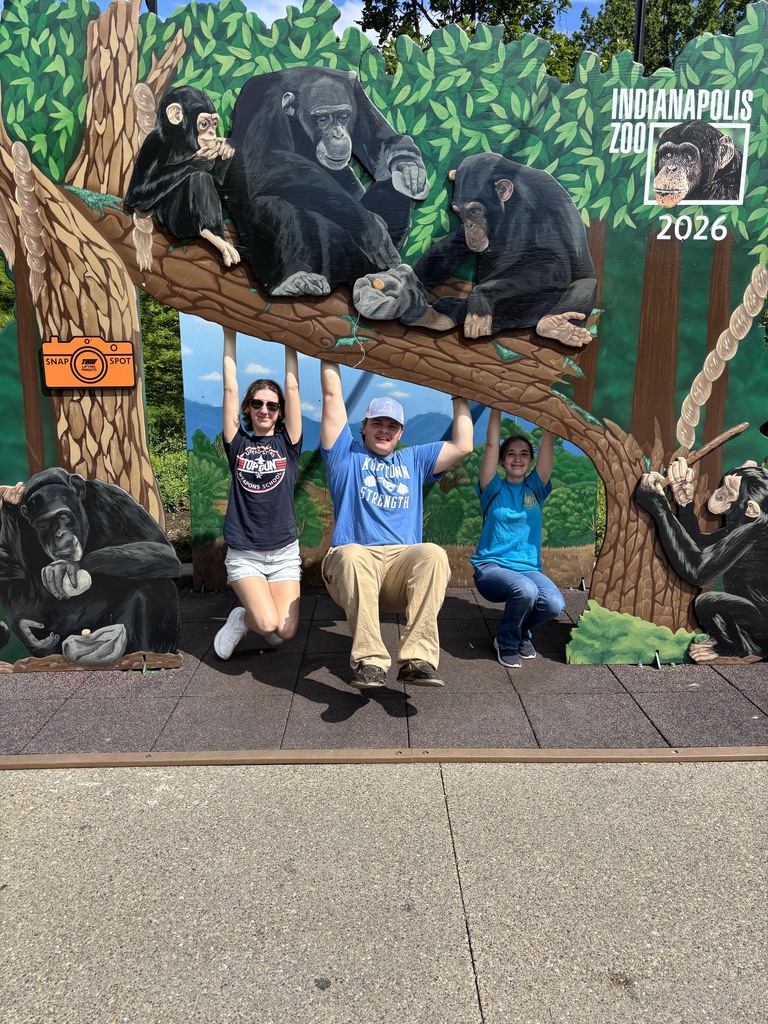 Three BCTC HOSA students pose playfully with an Indianapolis Zoo 2026 chimpanzee photo display.