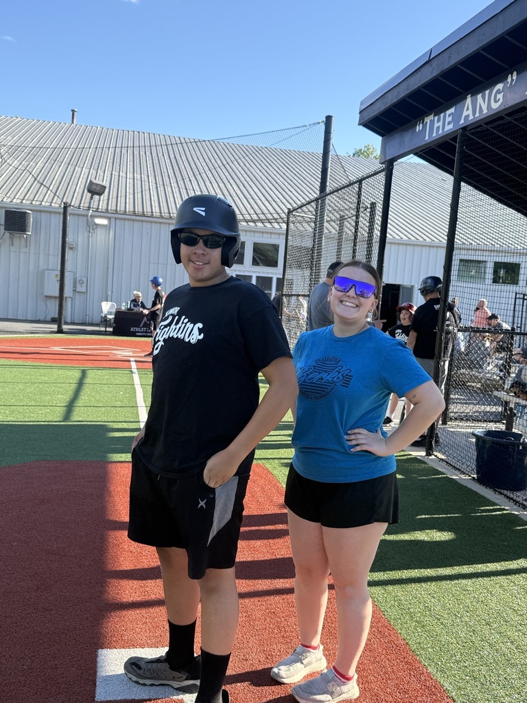 A BCTC student volunteer smiles beside a Dream League athlete near the dugout at Savage 61 Dream Field.