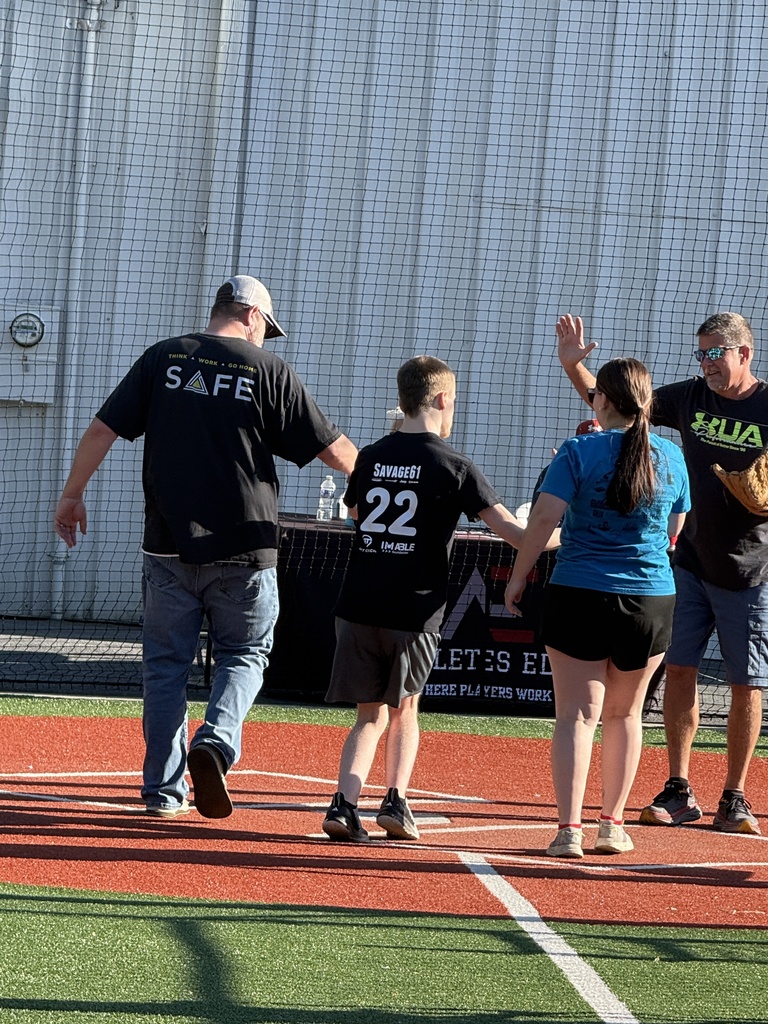 A Dream League athlete crosses home plate while volunteers offer support and a celebratory high-five.