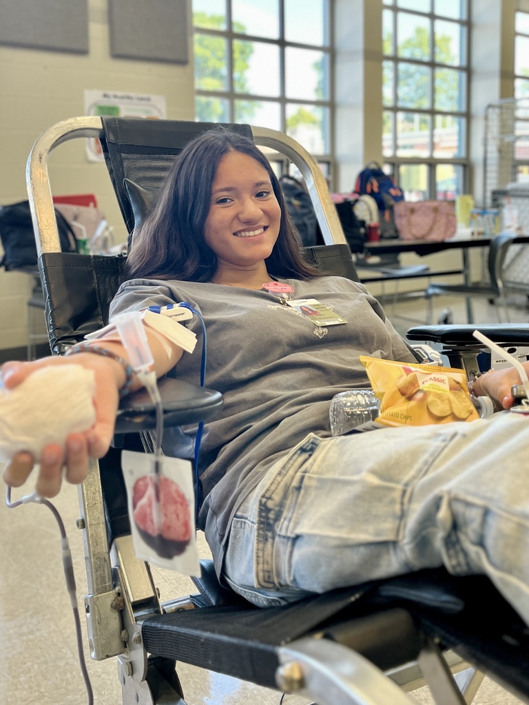 Person sitting in a chair, arm with IV line, holding a snack bag and a drink.