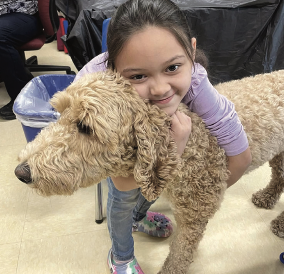 child hugging  tan Goldendoodle 