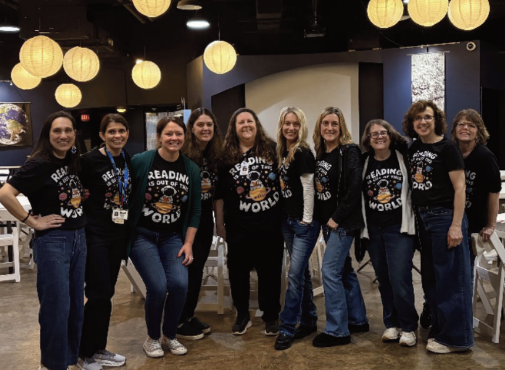 Group of staff smiling towrds camera in matching t-shirts for family literacy night
