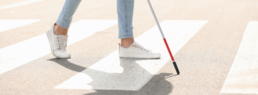 Person crossing the street using a white cane