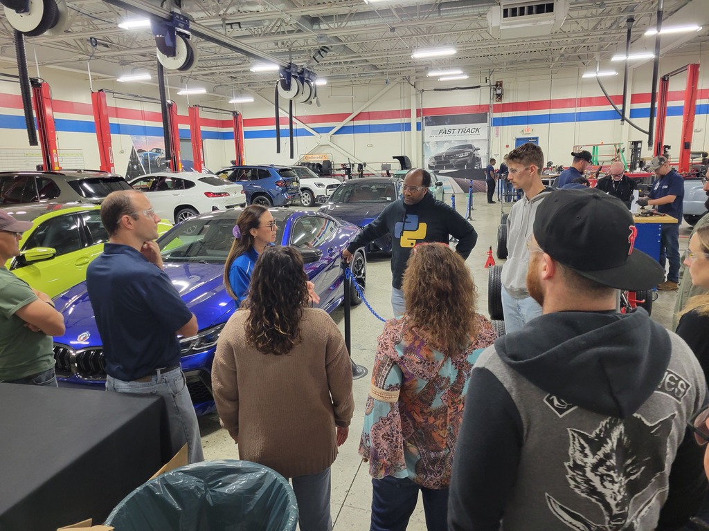 educators standing around an instructor at a car shop