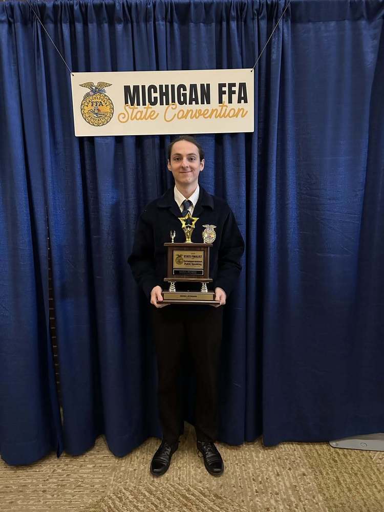 student in FFA uniform holding a trophy