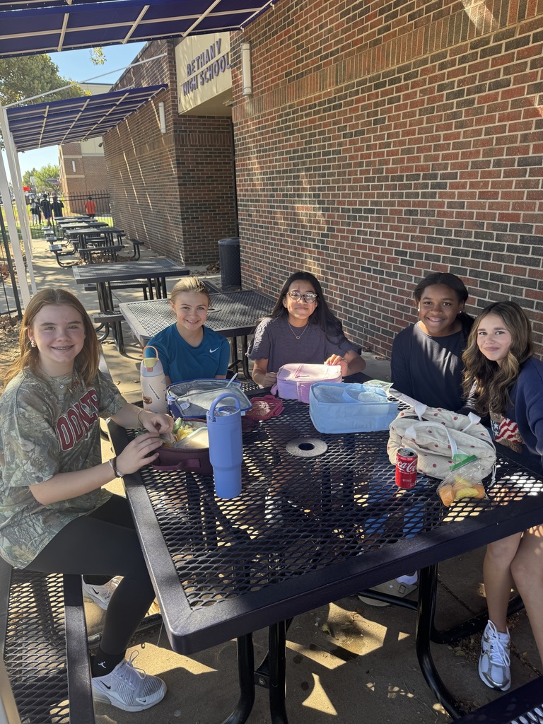 five young girls having lunch outside on a picnic table