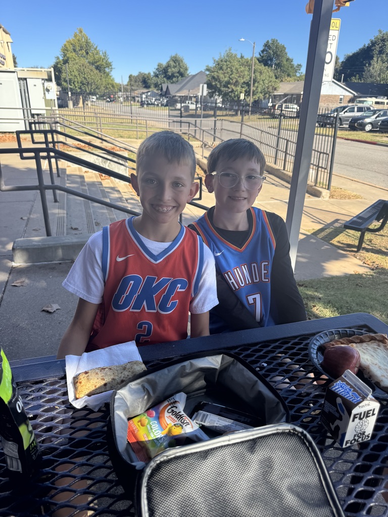 Two young boys eating lunch outside