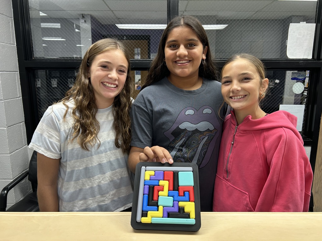 three girls smiling with a logic puzzle they solved