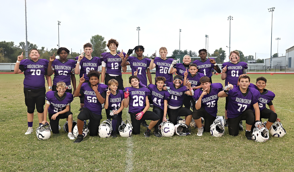 photo of football team in purple jerseys after a game holding up their fingers in the number one