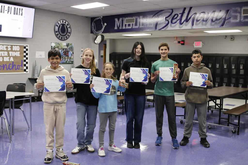 six students standing together holding Student of the Month certificates