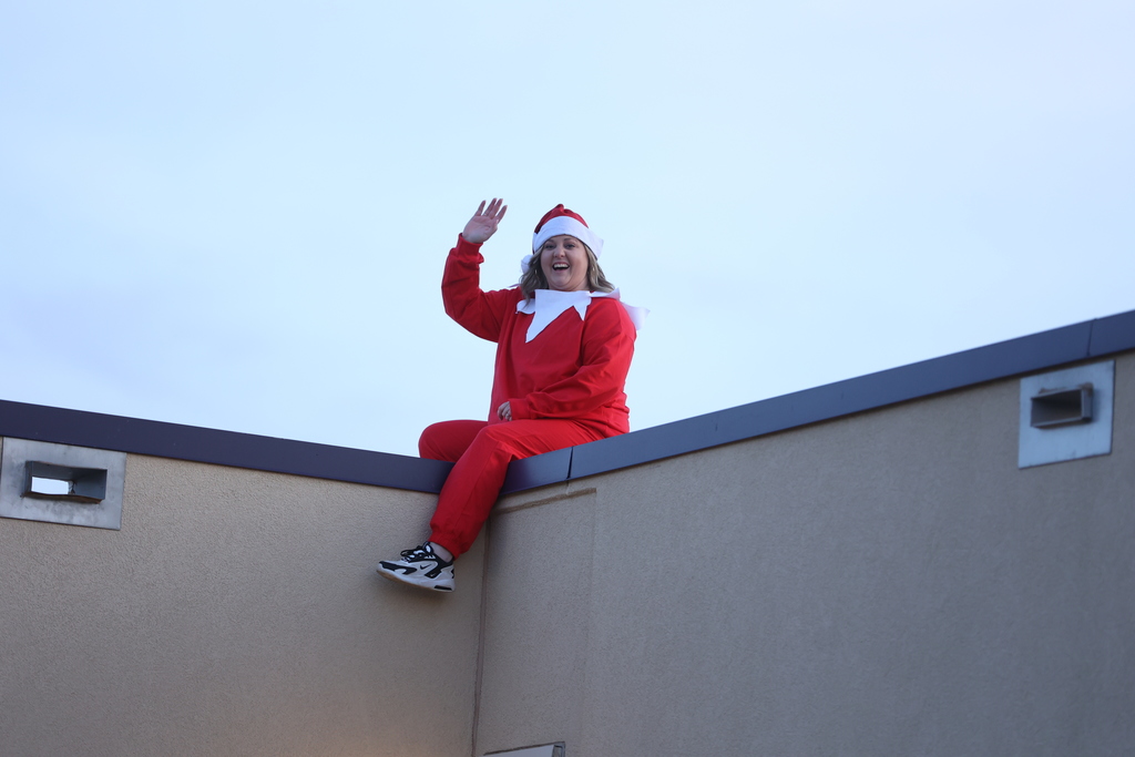 vice principal on the roof in elf costume, waving to students