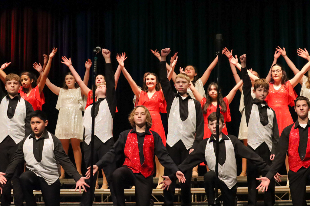 middle school show choir performing at contest wearing gray and red costumes
