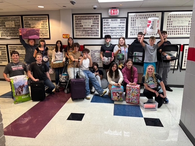 Students getting creative with the theme day of anything but a backpack. photo shows students with feed bags, suitcases, chairs, buckets, a stroller and more