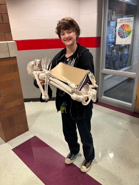 student holding a skeleton holding their school supplies