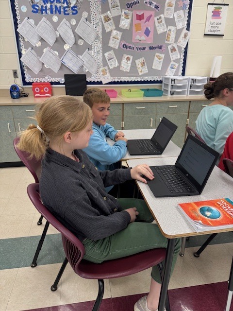 Students in Mrs. Starline’s language arts class took part in a fun writing challenge. Using illustrations displayed on the screen for inspiration, they wrote creative sentences and then combined their ideas to form a silly story, which they shared with a partner.