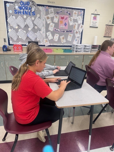 Students in Mrs. Starline’s language arts class took part in a fun writing challenge. Using illustrations displayed on the screen for inspiration, they wrote creative sentences and then combined their ideas to form a silly story, which they shared with a partner.