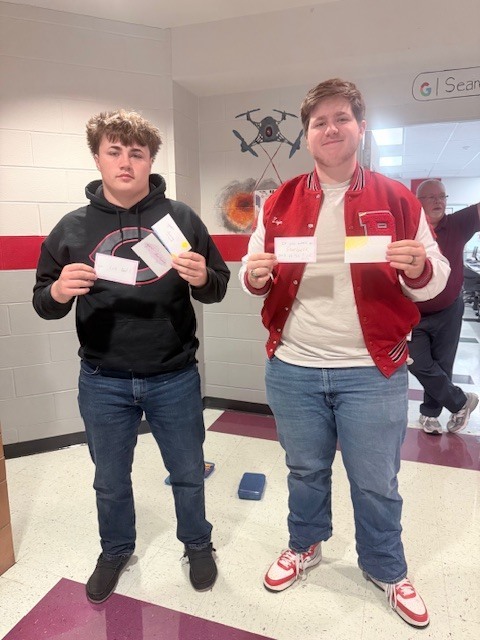 two male students holding kindness cards they made 