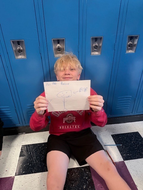 A student holding kindness cards he made 