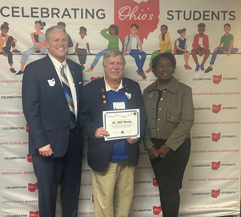 Bethel-Tate Schools VP Bill Shula poses for a photo with a man and woman in front of a Celebrating Ohio's Students back drop while holding a OSBA gold star certificate he earned.