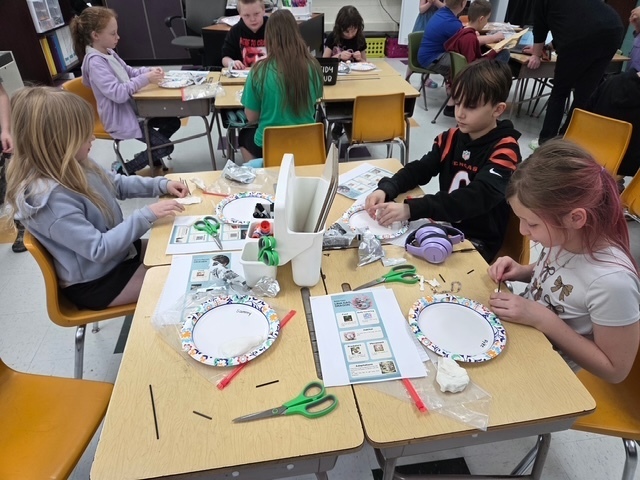 three students in the foreground working on their science art project