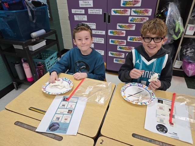 two boys smiling as they work on art project