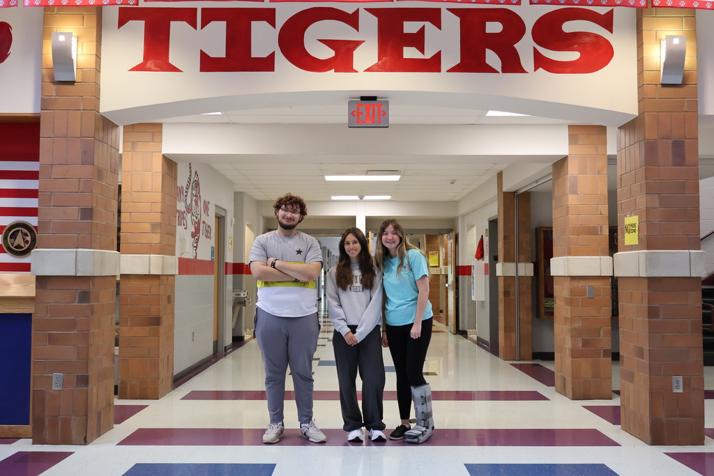 Three students standing in a hallway at BTHS. Tigers sign above their heads